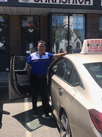 All Care instructor beside a school car outside the Hicksville office