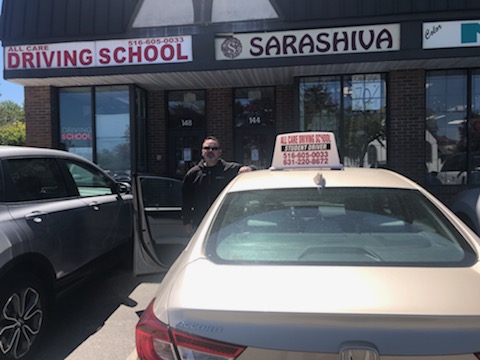 All Care instructor with a school car outside the Hicksville office